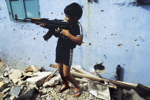 historicaltimes:  A Palestinian child plays with an AK assault rifle, Beirut, 1985