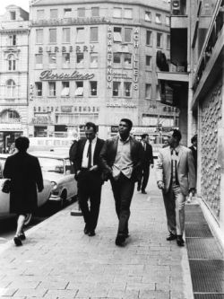 losetheboyfriend:  Muhammad Ali walks alongside boxing promoter and cornerman Angelo Dundee while a local newsman attempts to get an interview, Frankfurt, Germany; captured by Isaac Sutton (1966)