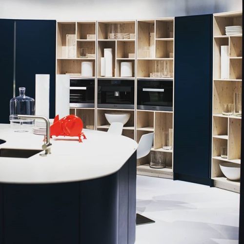 Dramatic contrast of blond wood cubicles of varying shapes and deep blue cabinetry. It’s an un