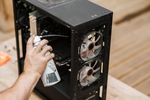 an image of a compressed air duster spraying dust out of a desktop computer.