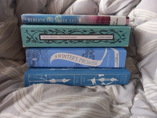 a stack of blue covered books on a grey and white background. 