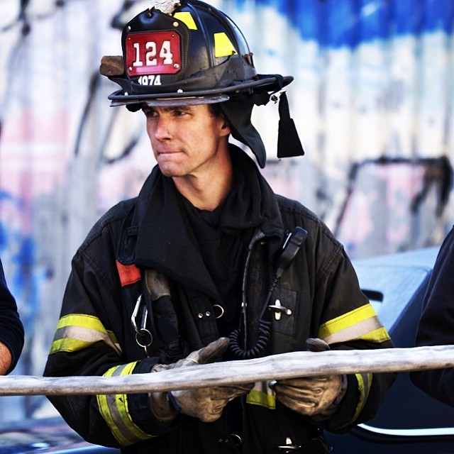 A NYFD firefighter helps to coil a hose back into a fire truck after a two hour battle with a blaze that destroyed two floors of an apartment building in Brooklyn, NY.