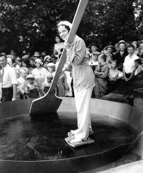 Woman in a giant frying pan with bacon tied to her feet before 7200 eggs are added to a record breaking omelette, Sweden, Nov 1931.