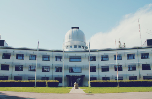 sci-universe:  The badass place in where I spend 5 days a week. (read and see more here) In front of the main building stands a sundial, a clock that tells the time of day by the position of the Sun:  and you can also see Estonian flags (blue-black-white)