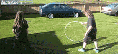 Four guys jump through a rolling hula hoop with careful timing