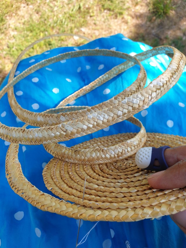 the flat crown of the hat with a lot of straw braid still to be sewn on 