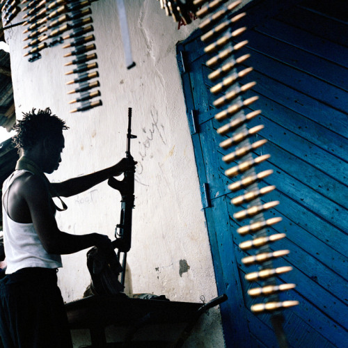 soldiers-of-war: LIBERIA. Tubmanburg. June 23, 2003. A LURD fighter cleans his AK-47 assault rifle i