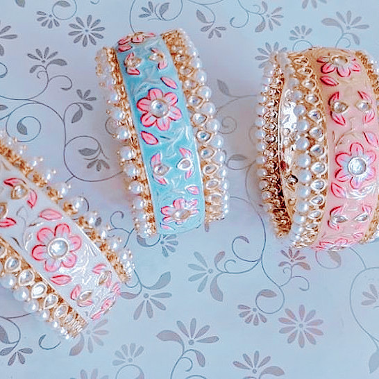 three meenakari enamelled bracelets in shades of white, pale blue and pale pink, set with semi precious stones and pretty floral motifs.