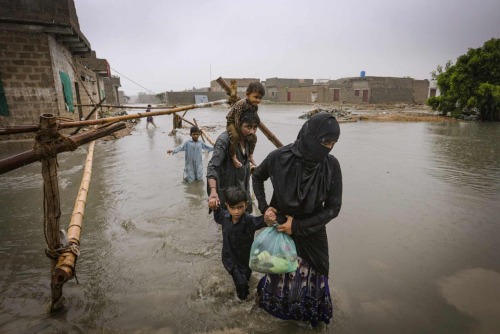 A family wade through a flooded area during a heavy monsoon rain in Yar Mohammad village after canal