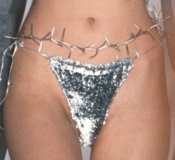 aloneandforsakenbyfateandbyman:A model wears a bikini bottom with a barbed wire Crown of Thorns for Todd Oldham’s 1998 Spring fashion show