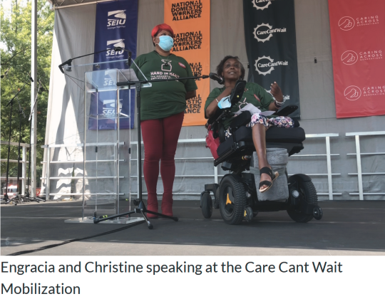 A photo of Christine Laing and Engracia Figueroa, two black women, the latter of which is disabled and using a motorized wheelchair, during the "Care Can't Wait" mobilization rally and "Communities of Care" art installation in Washington D.C., talking at a podium, representing the home care workers organization "Hand in Hand". Text says: Engracia and Christine speaking at the Care Cant Wait Mobilization.