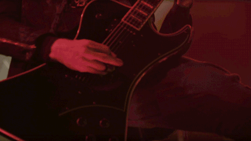A close-up of Phantom's hands as he plays his Fantomen guitar. You can see the black tape he's put around a couple of his fingers.