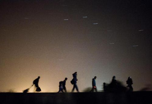 In this Sept. 13, 2015 photo taken with slow shutter speed migrants walk towards a checkpoint along 