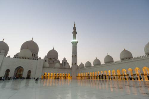 unrar:A view of domes, lighted arches, and a minaret at the Sheikh Zayed Grand Mosque at dusk, by Se