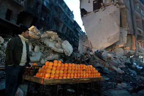globalwarmist: A man sells oranges along a damaged street in the Al Shaar area, Aleppo, Syria, Dec. 