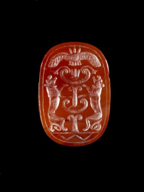 ancientpeoples:Cornelian scarab seal with two lions at a sacred tree under a winged sun disc.600 BC 