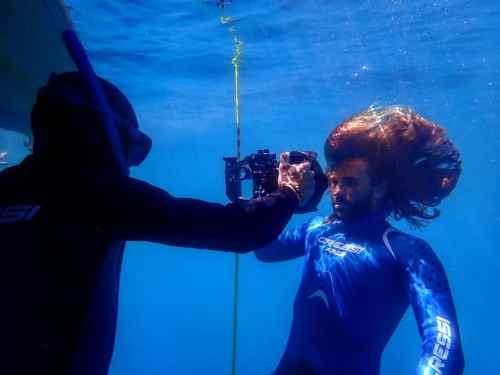 Long haired freediver barefaced underwater in wetsuit