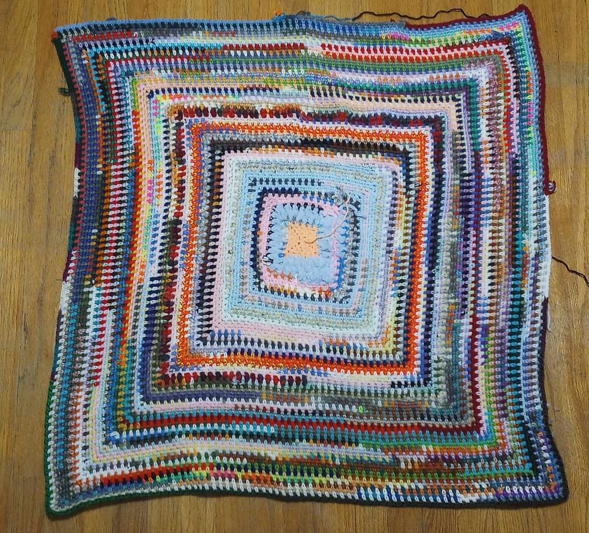 Square, moss stitch scrap yarn blanket, about 3 feet wide.