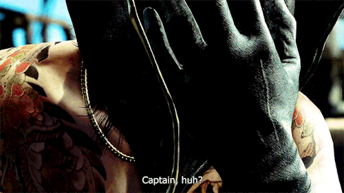 A close up of Majima putting on a pirate hat, lifting his head as he does. He's standing on a pirate ship. His subtitle says: Captain, huh?