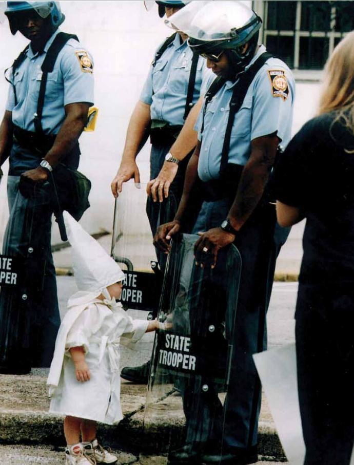 thesouthernthruway:
“ unexplained-events:
“ unexplained-events:
“ This photo was taken over 20 years ago by Todd Robertson during a KKK rally in northeast Georgia. One of the boys approached a black state trooper, who was holding his riot shield on...