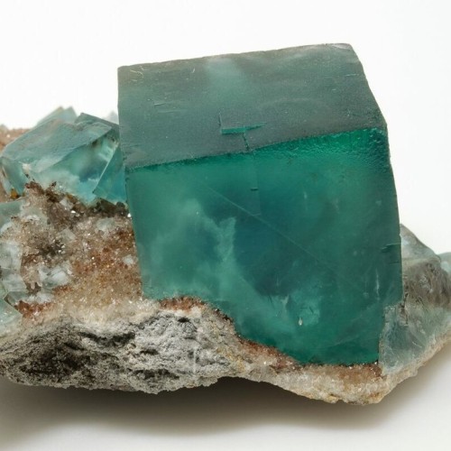 A beautiful, zoned, green fluorite crystal on a matrix of druzy quartz. This particular specimen sol