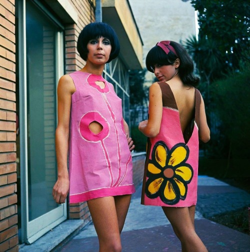 isabelcostasixties:Two models wear hand painted paper mini dresses with cut out holes in pink and br