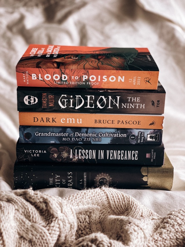 a book haul photo of a stack of books on a white sheet.