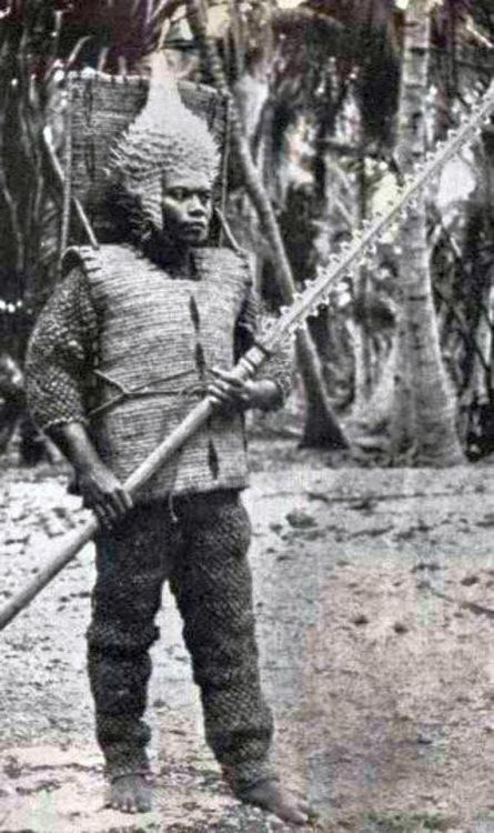Kirbati (Gilbert Islands) warrior with shark tooth sword, porcupine fish helmet, and coconut fiber a