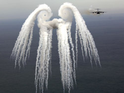 sixpenceee:  Smoke AngelThe cloud pictured above resulted from a series of flares released by an air force jet over the Atlantic Ocean. The jet that released the flares, a C-17 Globemaster III, is seen on the right. The flares release smoke, and the