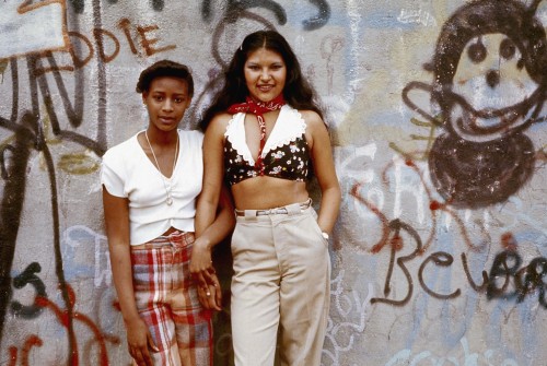 24kblk: danny lyon. two latina girls pose in front of a wall of graffiti. lynch park, brooklyn. june