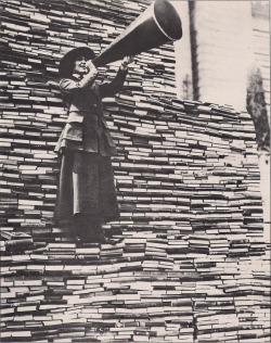bookporn:  Standing on a mountain of already donated volumes, an amiable barker calls for still more books from passers-by outside the New York Public Library on Fifth Avenue. 1910s (source) 