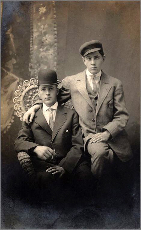 A fantastic studio portrait of two handsome fellows, seated on an equally admirable wickerwork chair
