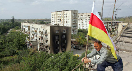 A man puts a South Ossetian flag on the roof of a building in Tskhinvali, the disputed territory of 