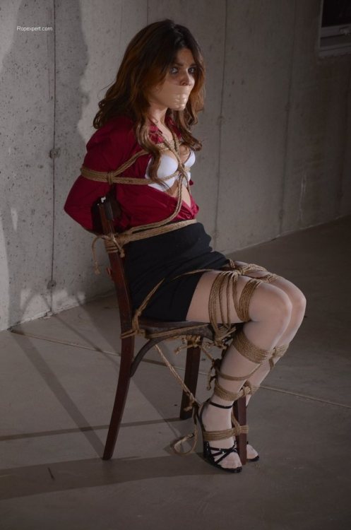 God, what a fucking perfect damsel in distress she is. Her outfit, the way she’s securely tied to a chair in the middle of an empty lit basement, the way she’s staring at her captor because the tape tightly plastered across her face has silenced her