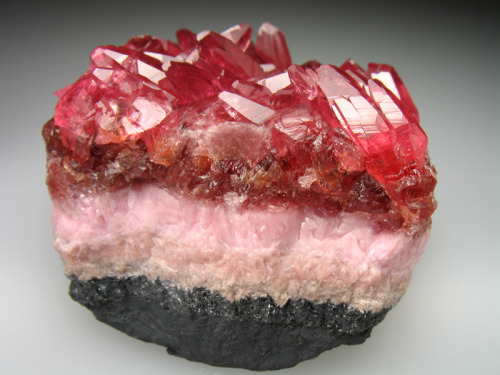Layers of orange, pink and red Rhodochrosite on Manganite - South Africa