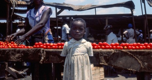 forafricans: A girl stands in front of her mother’s table. Harare, Zimbabwe. ©Tony Wright