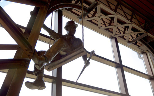A  bronze bridge-worker figure hangs perilously from the imitation steel bridge truss in the en