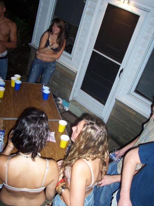 Two girls playing backyard strip beer pong, both end up topless as a result.