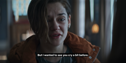 Text reads: But I wanted to see you cry a bit before. A close-up of a white woman with short brown hair who cries. She wears multiple, small, silver earrings and a rust-coloured puffer jacket.