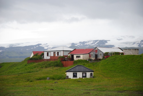 Little houses in front of a big glacier.  There are two major glaciers in Iceland that stretch acros