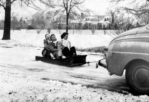 Sledding down the road behind a car, 1947