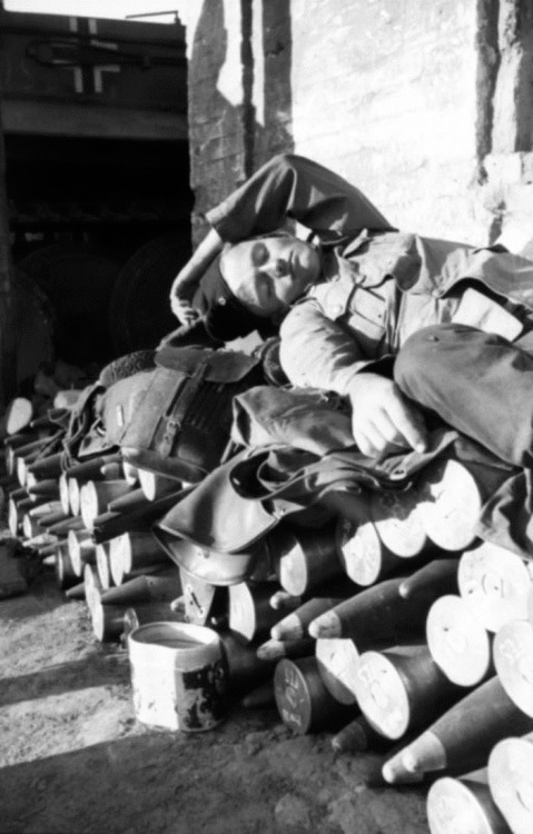 A German soldier naps upon a bed of shells on the Eastern Front. Russia, Soviet Union. July 1943.