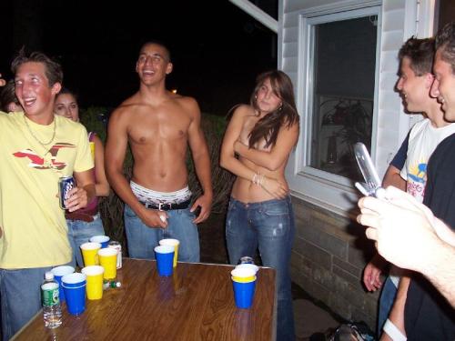 Two girls playing backyard strip beer pong, both end up topless as a result.