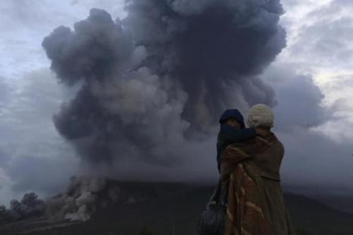 sickpage: A mother holds her son as they watch the eruption of Mount Sinabung at Berastepu village i