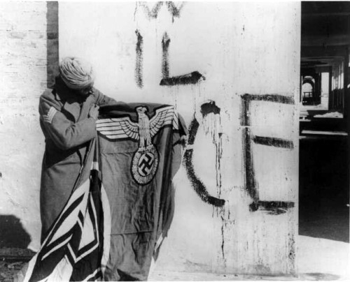 A Sikh soldier of the Indian Army holds a captured Nazi flag, Italy, World War II.
