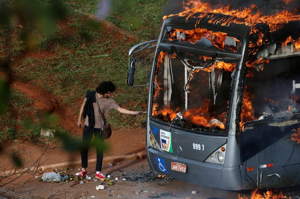 troposphera:  A man lights up his cigarette with the flames of a bus burned by  anti-government