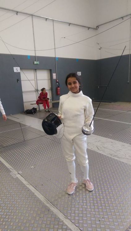 [ID: an epee fencer saluting the camera.]Anica Camacho, who made history at age 12 when she won Guam