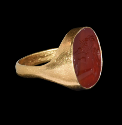 gemma-antiqua:Ancient Roman gold ring with a carnelian intaglio depicting Vulcan creating a helmet, 