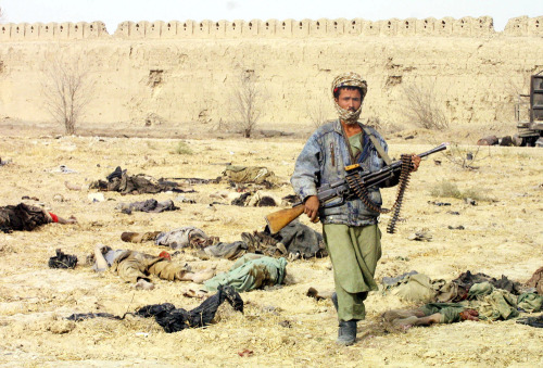 cumsoline:A Northern Alliance fighter walks through a yard littered with bodies of pro-Taliban force