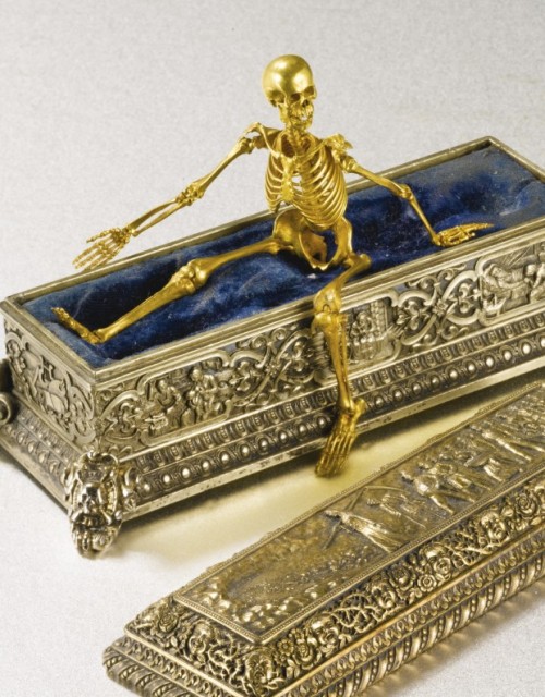 “The fully articulated human skeleton in a velvet-lined coffin with three panels showing 